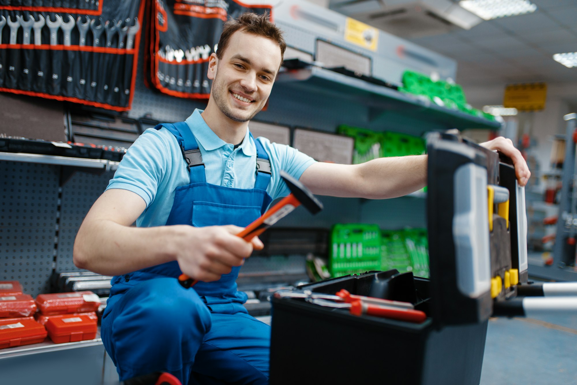 Happy male worker choosing toolbox in tool store