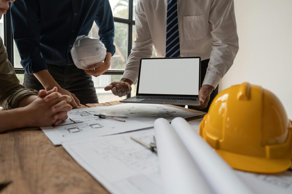 Team of engineers meeting to report project construction on laptop screen